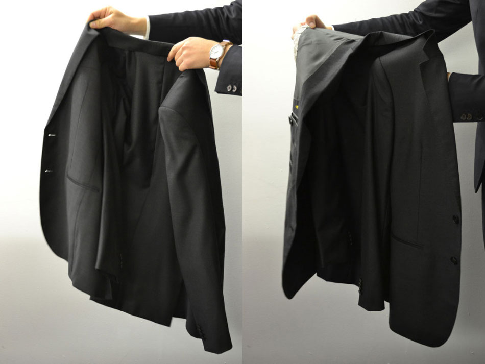 hand holding up a suit jacket showing how to fold a suit jacket