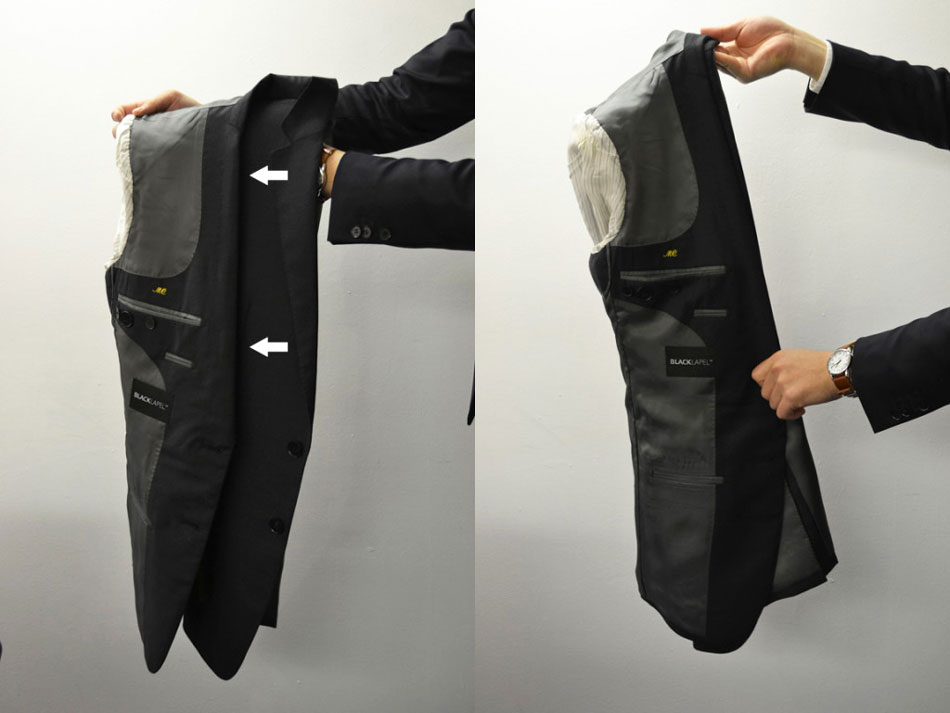 hand holding up a suit jacket folding the shoulder portion of the suit jacket