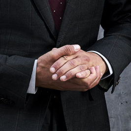 close up of man's hands wearing a black suit