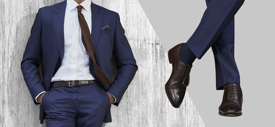 man wearing a navy suit with matching brown tie, brown belt, and brown oxfords