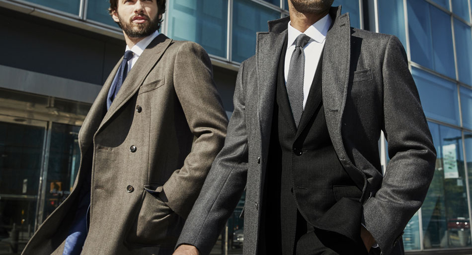 two men walking side by side wearing brown and gray topcoats