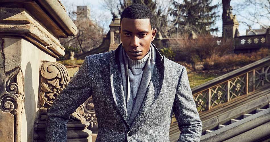 man outdoors wearing a gray turtleneck sweater under a gray wool topcoat 