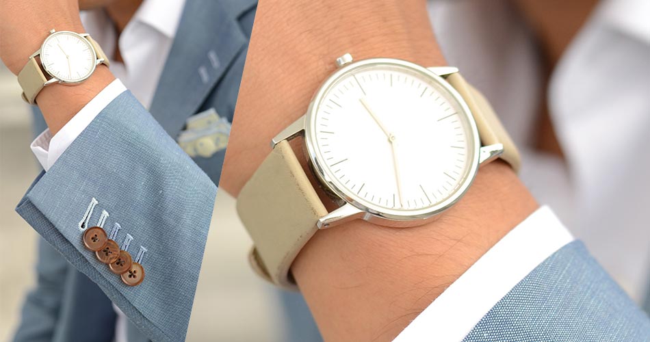 man's wrist in light blue suit wearing a leather gold watch