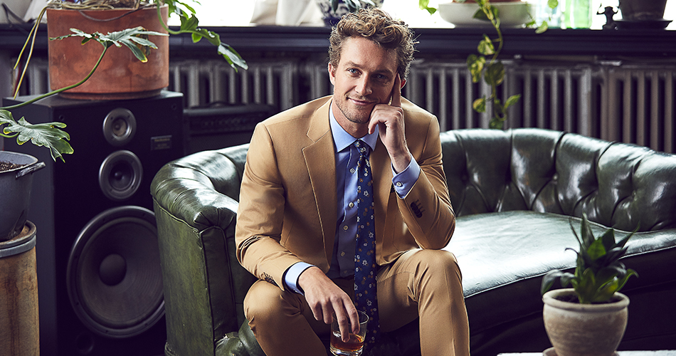 man wearing a khaki suit with a drink