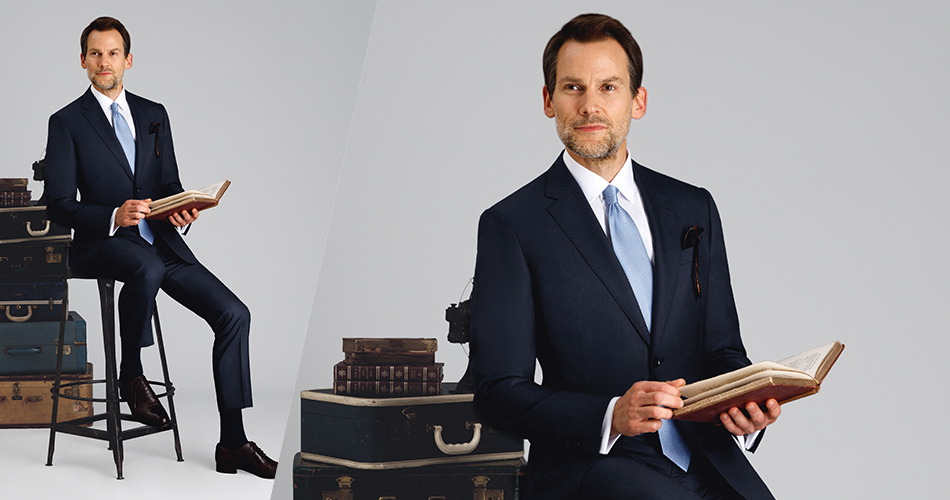 man on a chair with a dark blue suit and book