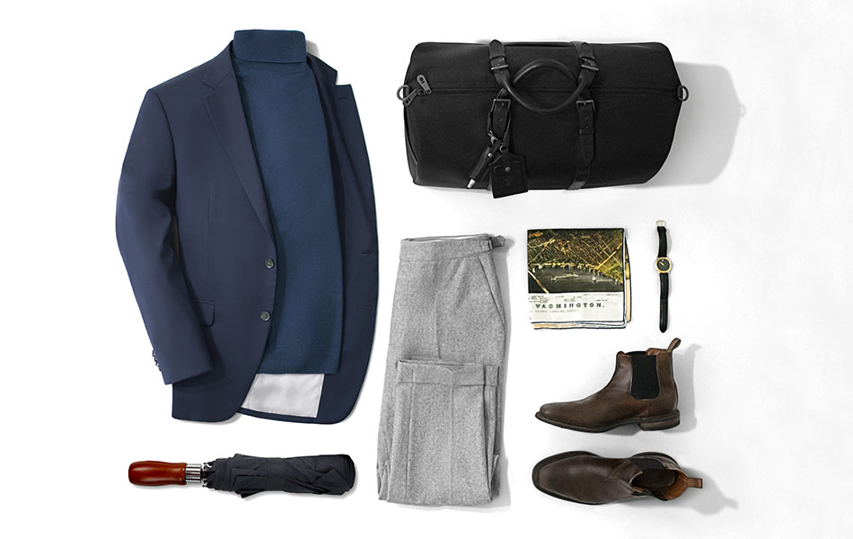 navy blazer outfit with navy turtleneck and gray pants and a duffle bag