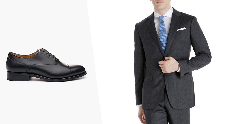 sideview of black oxfords paired with a man in dark charcoal suit and a blue tie