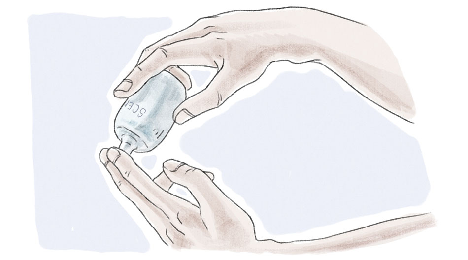 person tipping a cologne bottle onto two fingers