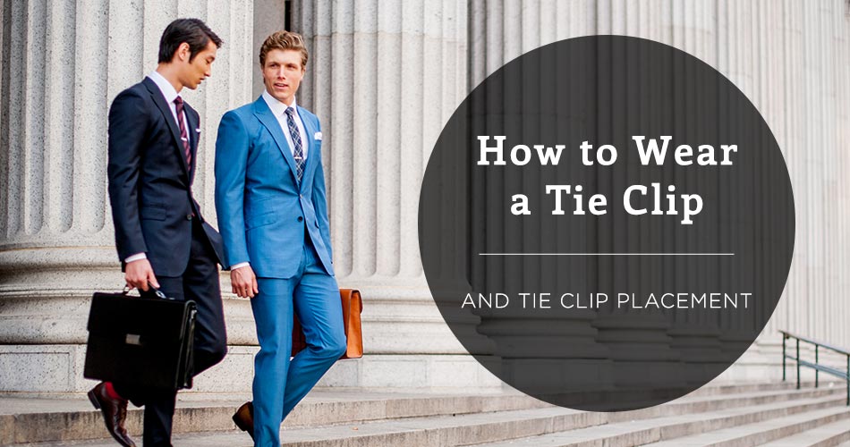 two men wearing suits walking down a staircase holding a brief case with text in a black circle overlay reading 'how to wear a tie clip and tie clip placement'