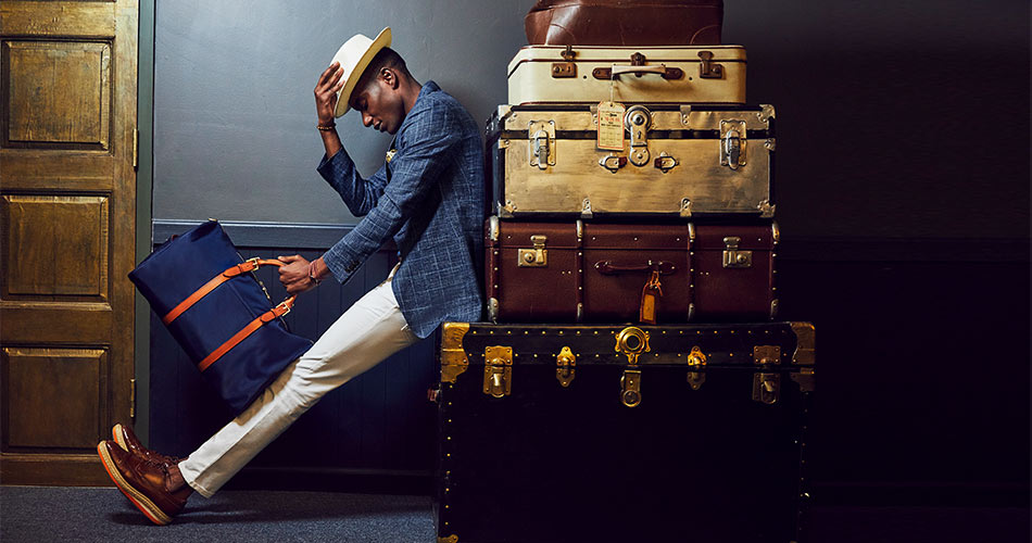 man wearing linen suit blazer with white chinos with hat and a bag