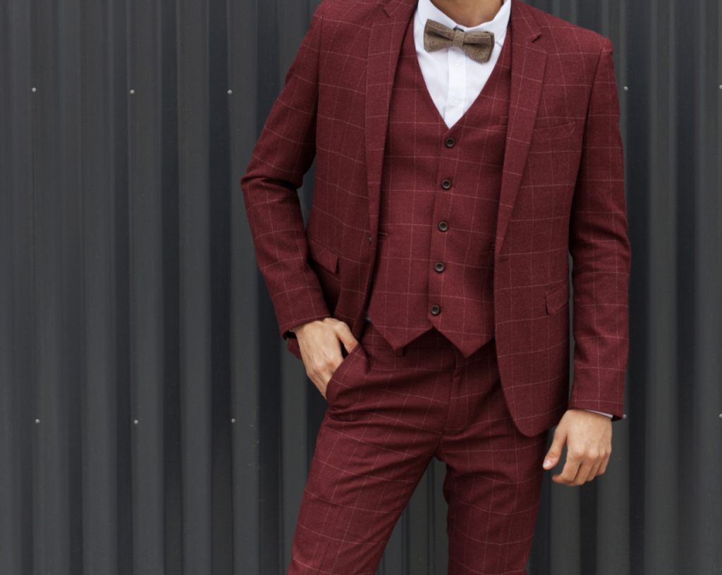 A well-dressed man wearing a burgundy suit and a stylish bow tie.